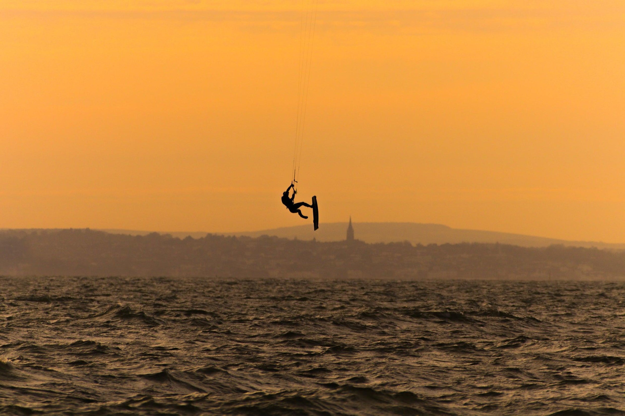 silhouette-of-a-person-kite-surfing-in-wavy-water - Ready Sweat Go